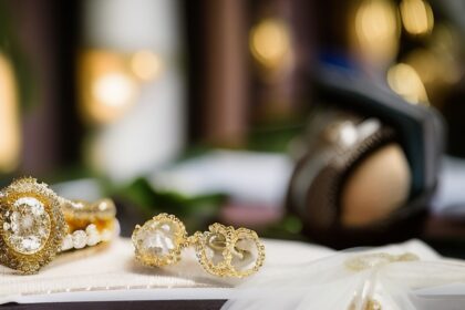suknia ślubna leżąca na stole a obok niej złota biżuteria ślubna