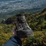 a person holding up a pair of shoes on top of a mountain