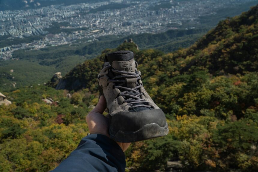 a person holding up a pair of shoes on top of a mountain